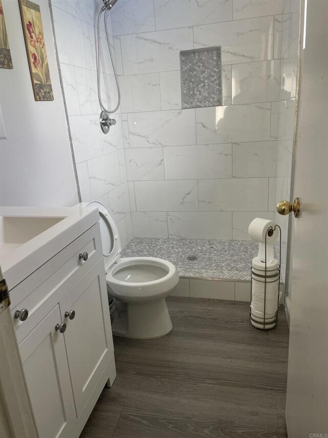 bathroom featuring toilet, a shower stall, wood finished floors, and vanity