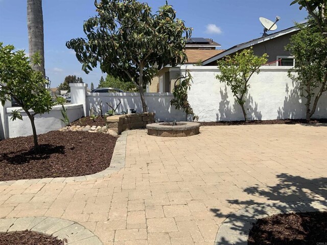 obstructed view of property featuring a patio, fence, a fire pit, and stucco siding