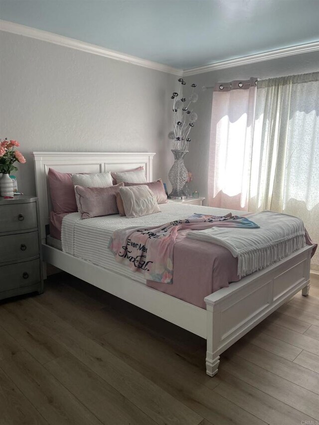 bedroom featuring crown molding and wood finished floors