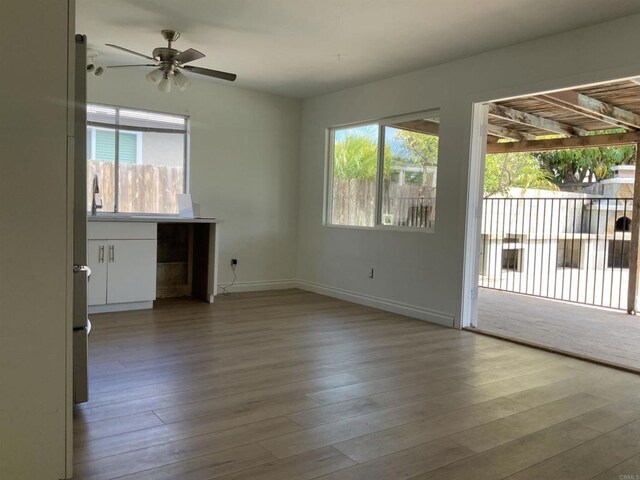 unfurnished living room with a ceiling fan, wood finished floors, and a healthy amount of sunlight