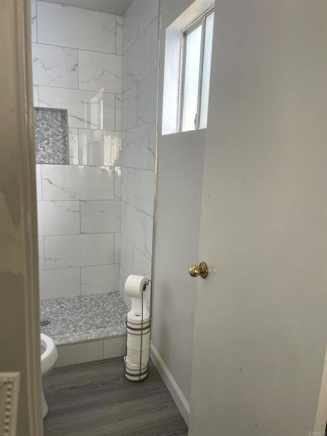 full bath with toilet, baseboards, wood finished floors, and a stall shower