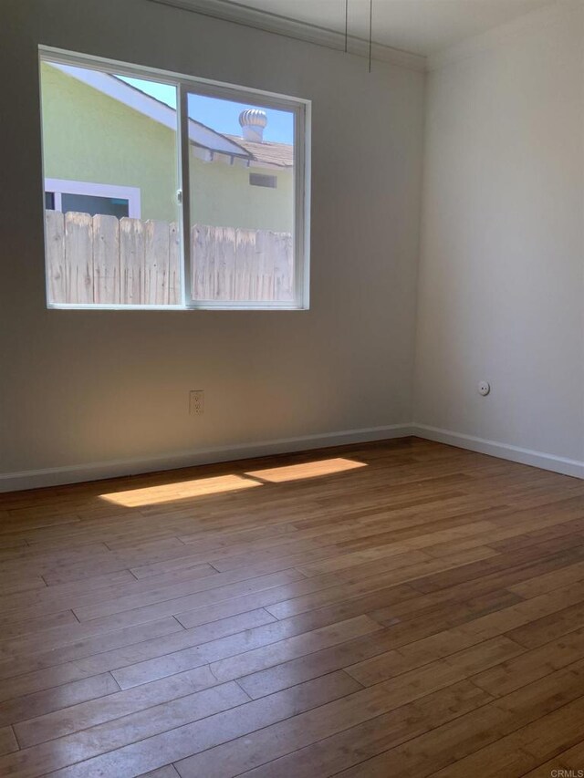 empty room with baseboards, ornamental molding, and wood-type flooring