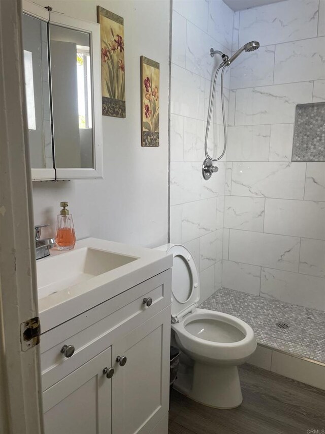 bathroom featuring vanity, a stall shower, toilet, and wood finished floors