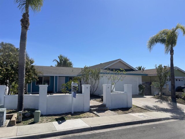 view of front of house featuring driveway, a fenced front yard, and a garage