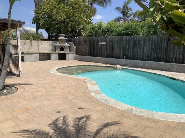 view of pool featuring an outdoor fireplace, a fenced backyard, a patio area, and a fenced in pool