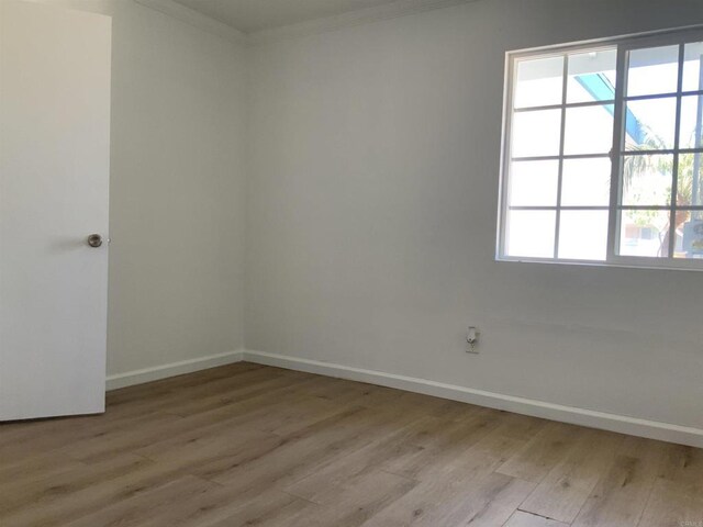 unfurnished room featuring crown molding, baseboards, and light wood finished floors