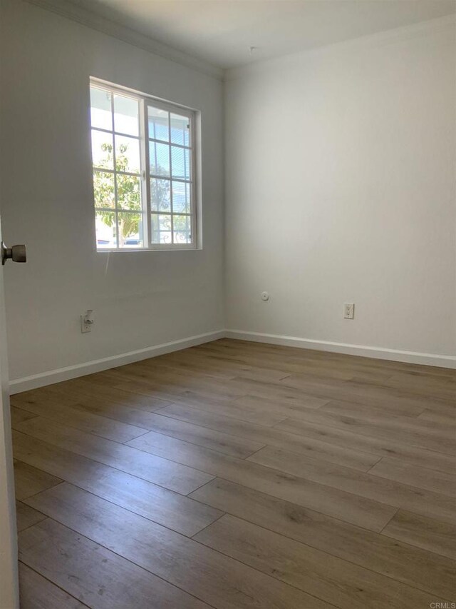 unfurnished room featuring baseboards, ornamental molding, and wood finished floors