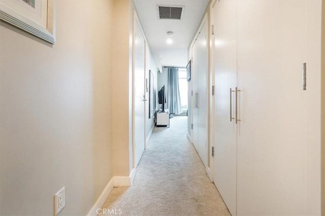 hall with light carpet, visible vents, and baseboards