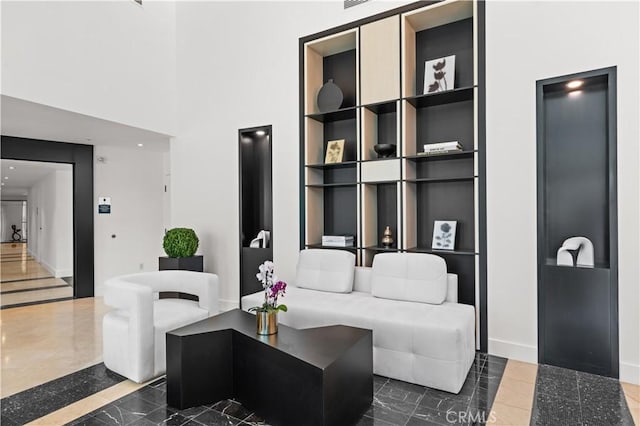 living room featuring built in features, baseboards, and a towering ceiling