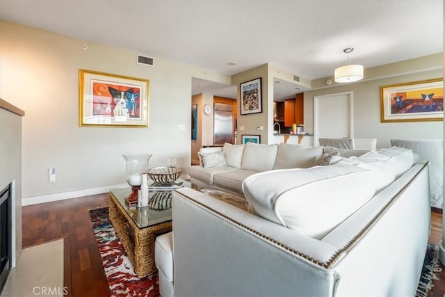 living area with wood finished floors, visible vents, and baseboards