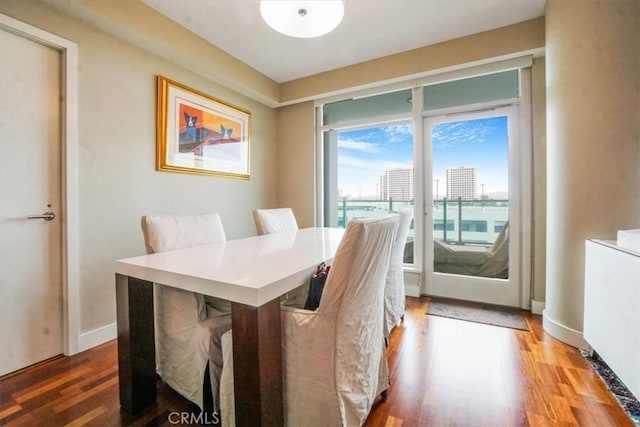 dining space with a view of city, baseboards, and wood finished floors