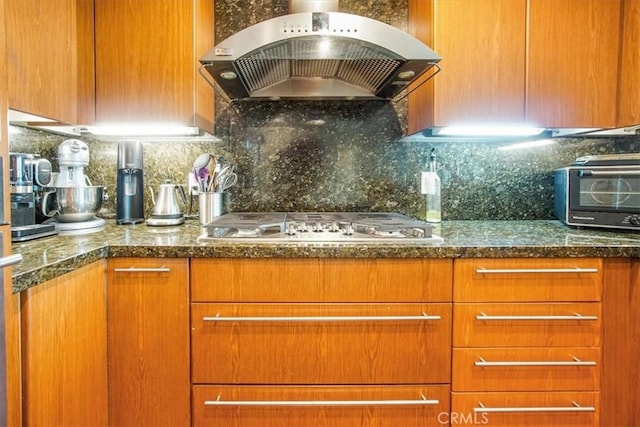 kitchen featuring decorative backsplash, ventilation hood, a toaster, and stainless steel gas stovetop