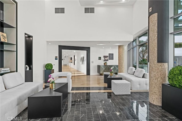 living area featuring marble finish floor, visible vents, and a towering ceiling