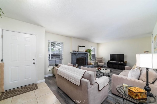 living area with light tile patterned floors, a fireplace, and baseboards