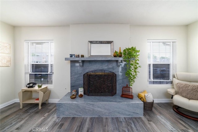 living area with a fireplace, baseboards, and wood finished floors