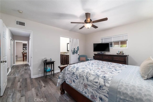 bedroom with a ceiling fan, wood finished floors, visible vents, baseboards, and ensuite bath