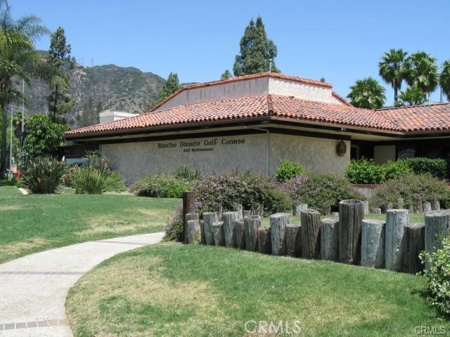 view of home's exterior featuring a lawn, a mountain view, a tile roof, and stucco siding