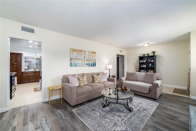 living room with baseboards, visible vents, and light wood-type flooring