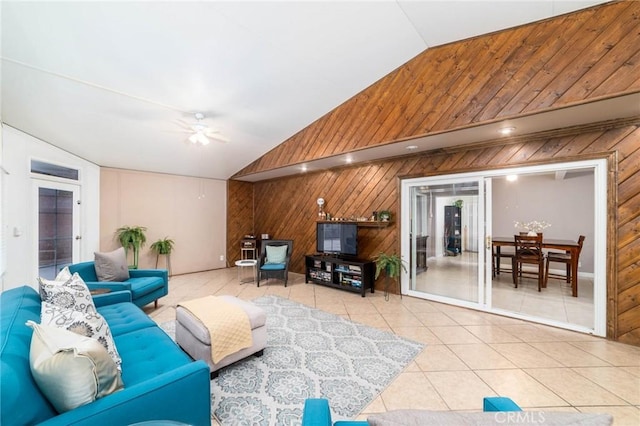 tiled living room with ceiling fan, wood walls, and vaulted ceiling