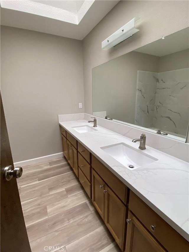 full bathroom featuring double vanity, wood finished floors, a shower, and a sink
