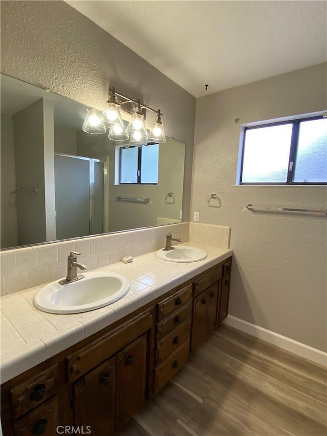 full bathroom with double vanity, wood finished floors, and a sink
