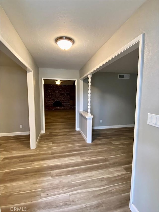 corridor with visible vents, baseboards, and wood finished floors