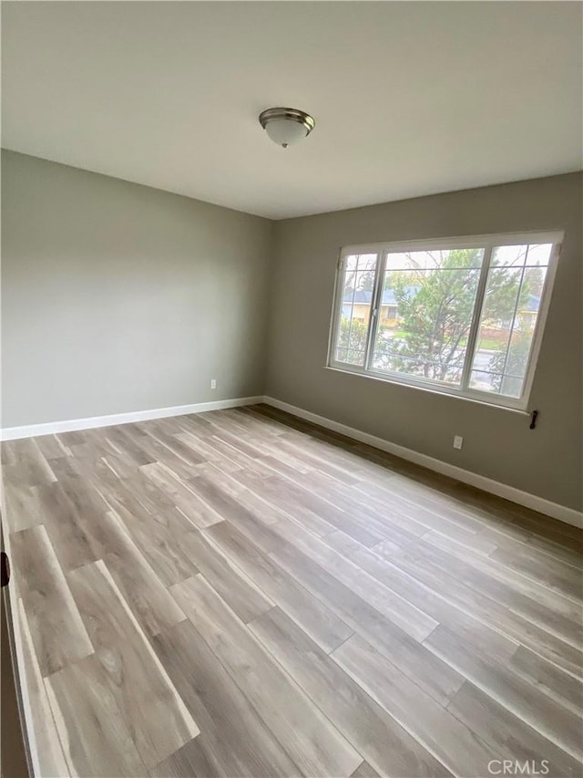 empty room with a healthy amount of sunlight, baseboards, and wood finished floors