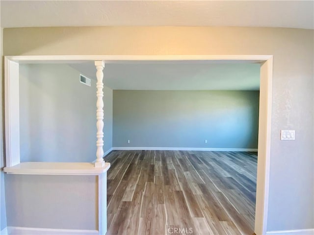 spare room with dark wood-style floors, visible vents, and baseboards