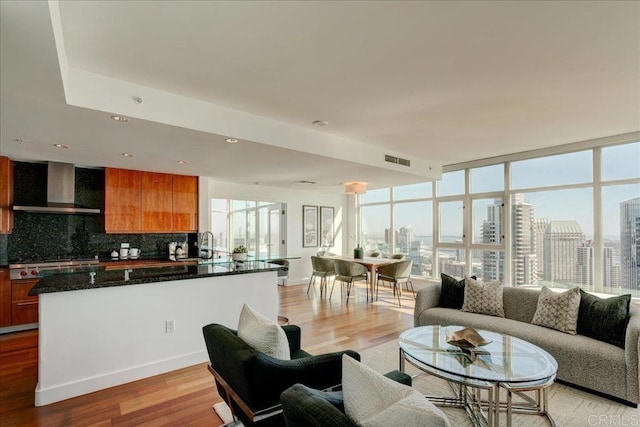 living room featuring a wall of windows, visible vents, light wood-style floors, and a city view