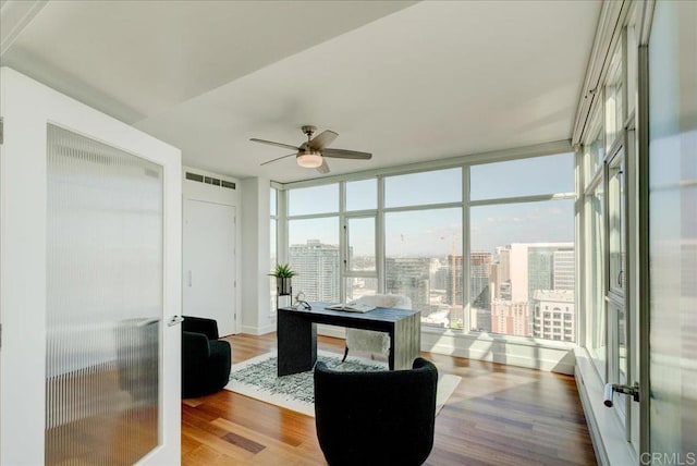 office space with a ceiling fan, visible vents, floor to ceiling windows, french doors, and a city view