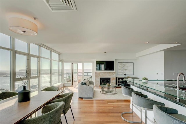 interior space featuring a glass covered fireplace, light wood-style flooring, recessed lighting, and visible vents