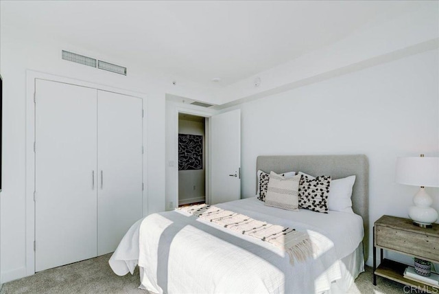 bedroom featuring visible vents, light colored carpet, and a closet