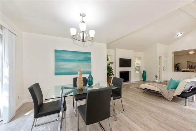 dining space featuring an inviting chandelier, light wood finished floors, baseboards, and a fireplace