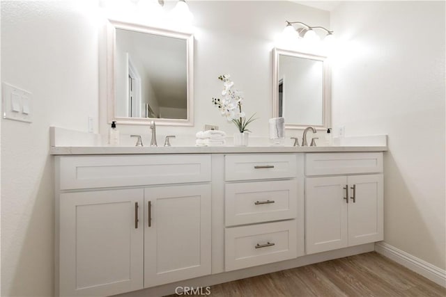 full bathroom featuring double vanity, baseboards, a sink, and wood finished floors