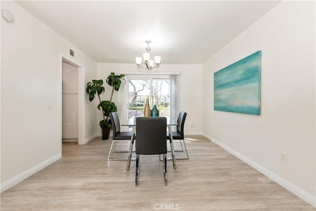 dining room featuring baseboards, visible vents, light wood finished floors, and a notable chandelier