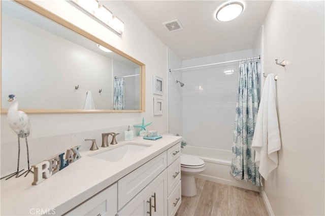 bathroom featuring shower / bath combo, vanity, toilet, wood finished floors, and visible vents