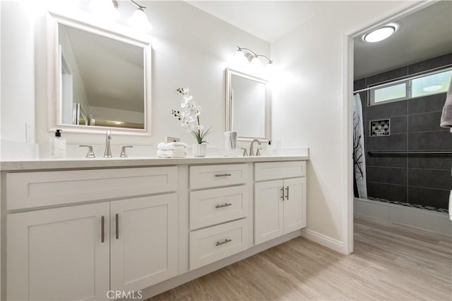 bathroom featuring tiled shower, a sink, and wood finished floors