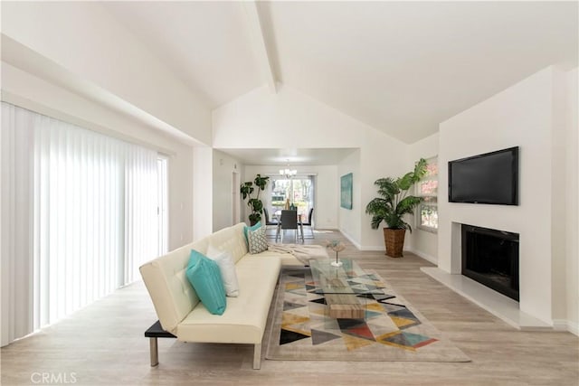 living area with beam ceiling, light wood finished floors, a fireplace with raised hearth, high vaulted ceiling, and baseboards