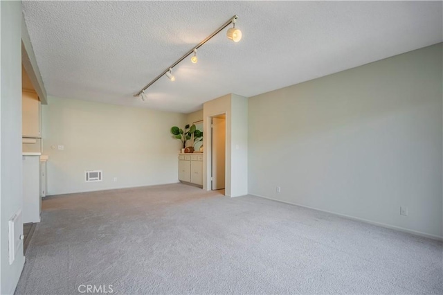 unfurnished room with light carpet, track lighting, a textured ceiling, and visible vents