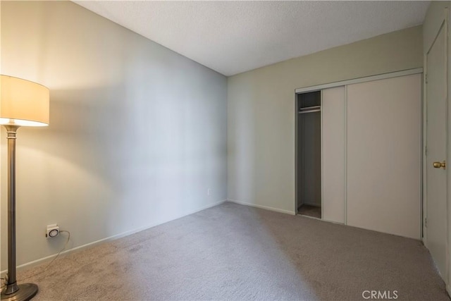 unfurnished bedroom featuring a closet, a textured ceiling, and carpet flooring