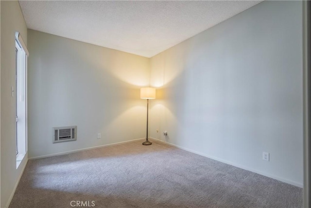 empty room featuring carpet flooring, a textured ceiling, and baseboards