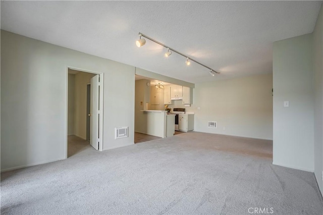 unfurnished living room with visible vents, light colored carpet, rail lighting, and a textured ceiling