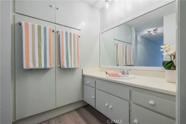 bathroom with vanity, wood finished floors, and a textured ceiling