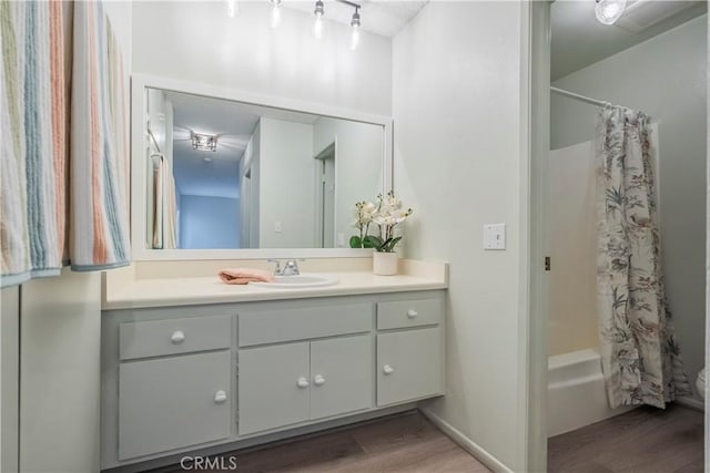 bathroom with baseboards, shower / bath combo, wood finished floors, and vanity