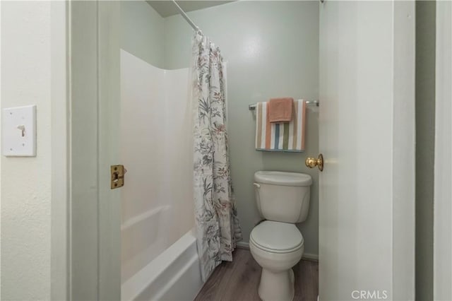 bathroom featuring toilet, shower / bath combo with shower curtain, and wood finished floors