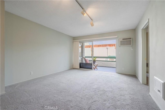 unfurnished room featuring a wall unit AC, carpet floors, and a textured ceiling