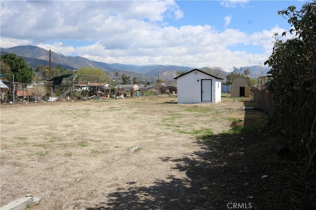 view of yard featuring an outbuilding, a storage unit, fence, and a mountain view