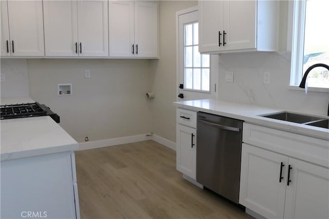 kitchen with white cabinets, dishwasher, light wood-style flooring, and a sink