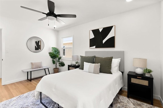 bedroom with a ceiling fan, baseboards, and wood finished floors