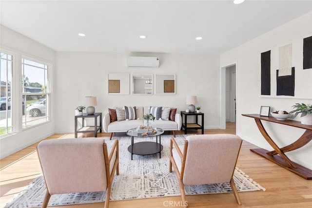 living area featuring recessed lighting, baseboards, an AC wall unit, and light wood-style flooring